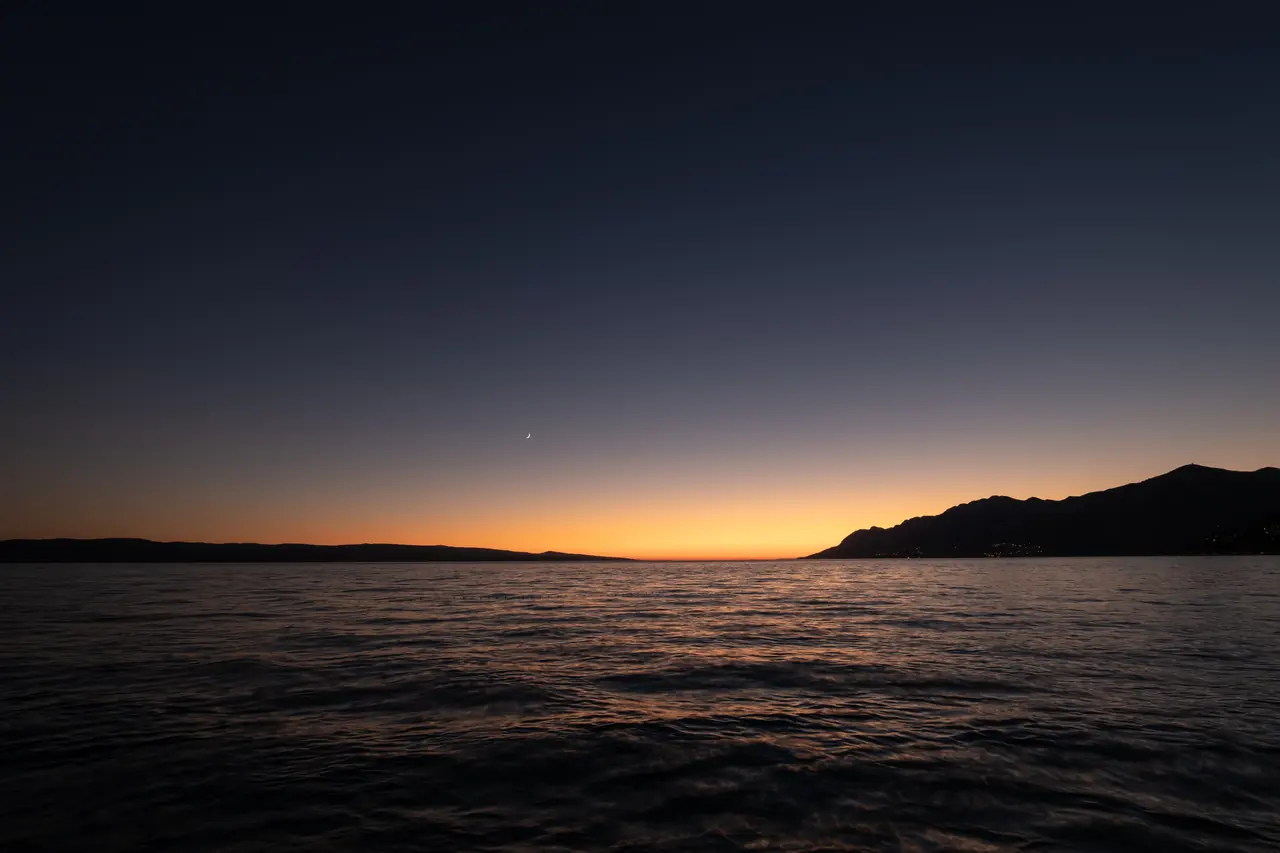 Horizon méditerranéen au crépuscule, bande orangée au-dessus d'une côte en silhouette