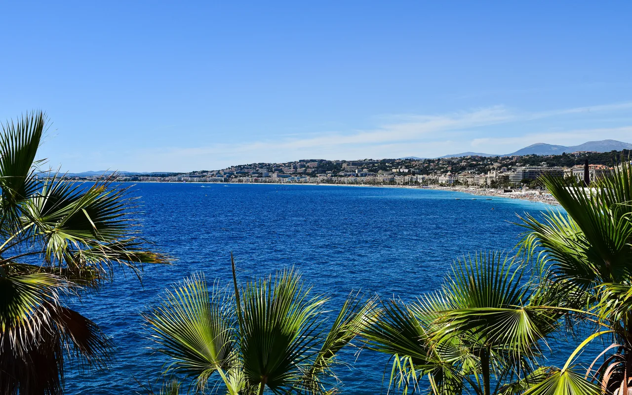 La baie des Anges vue à travers les palmiers du front de mer de Nice